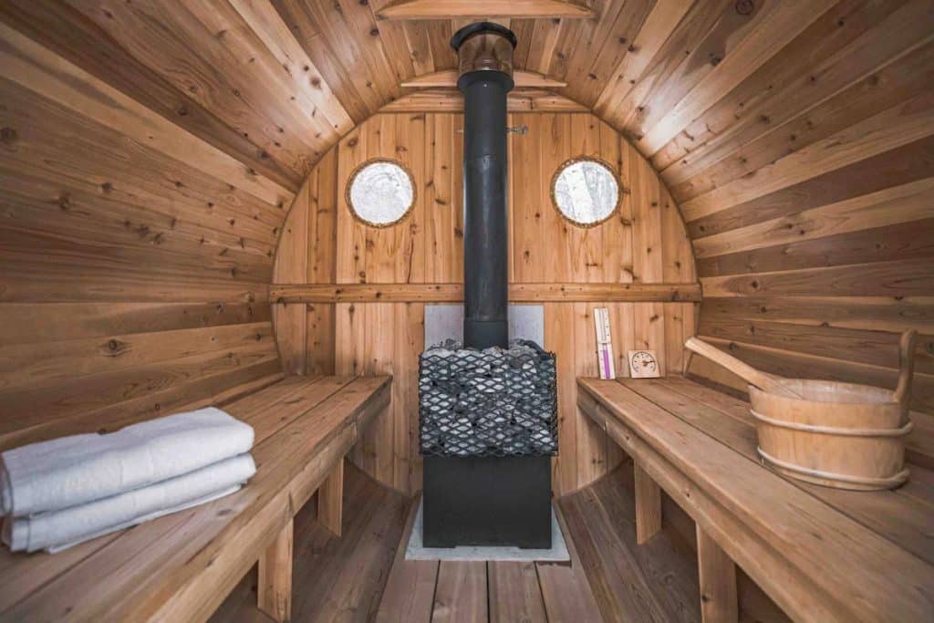 inside sauna with benches on both sides and wood stove at back