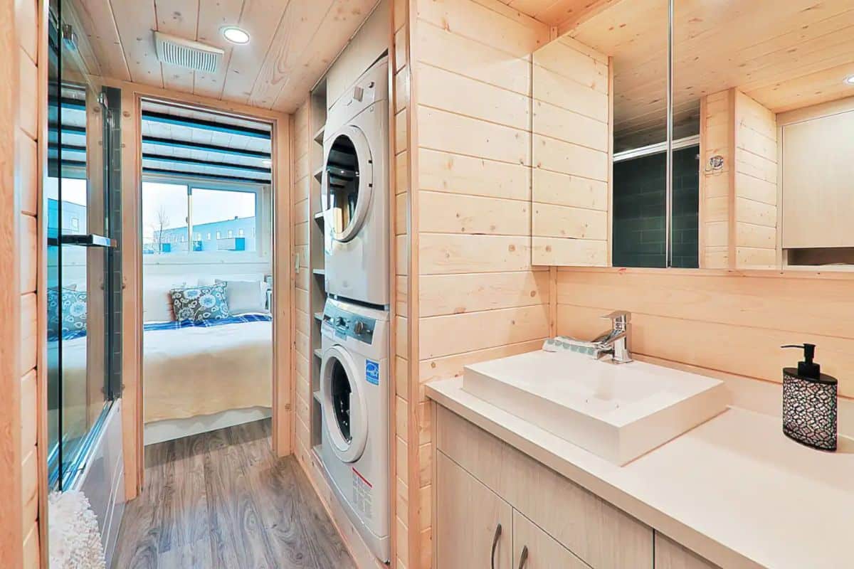 stacking washer and dryer next to white bowl sink in tiny home