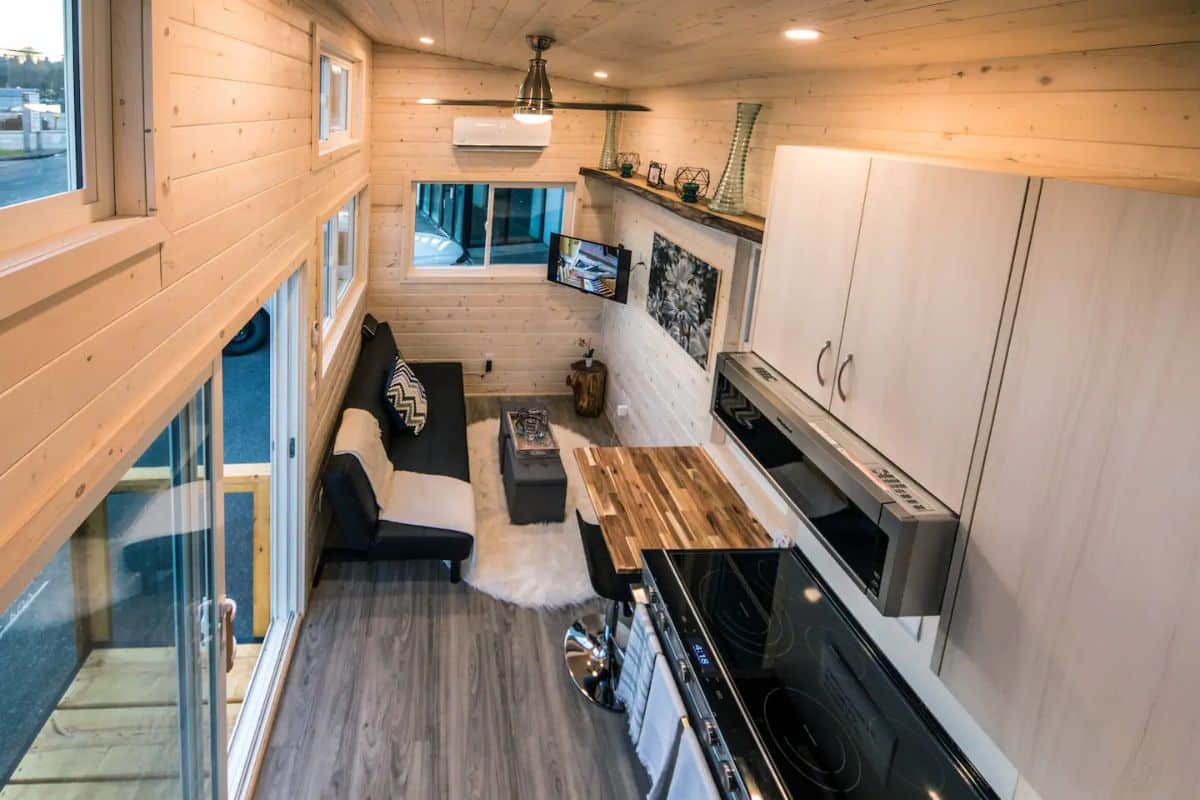 light wood cabinets above dark and butcher block countertops inside tiny home