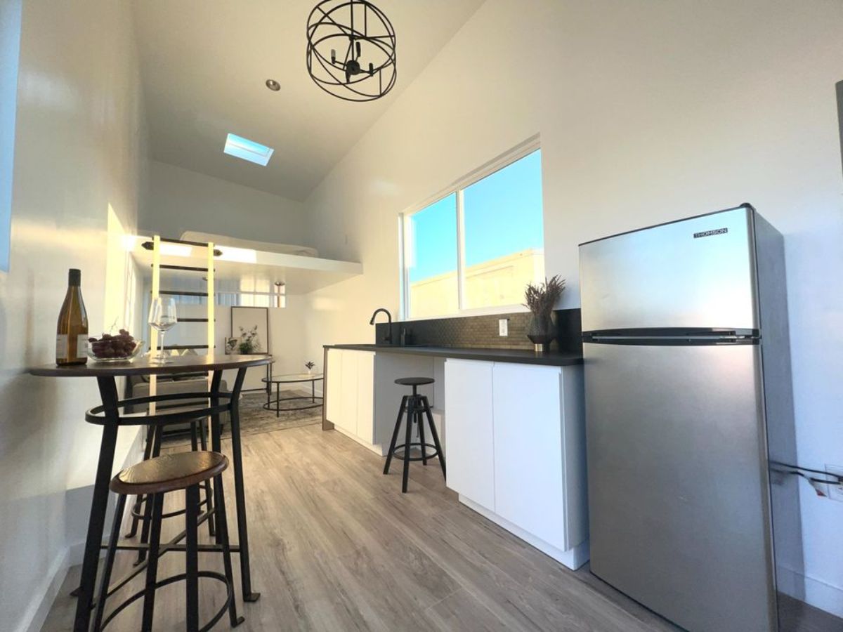 Stunning black countertop with all the appliances with refrigerator in kitchen area of travel tiny home trailer