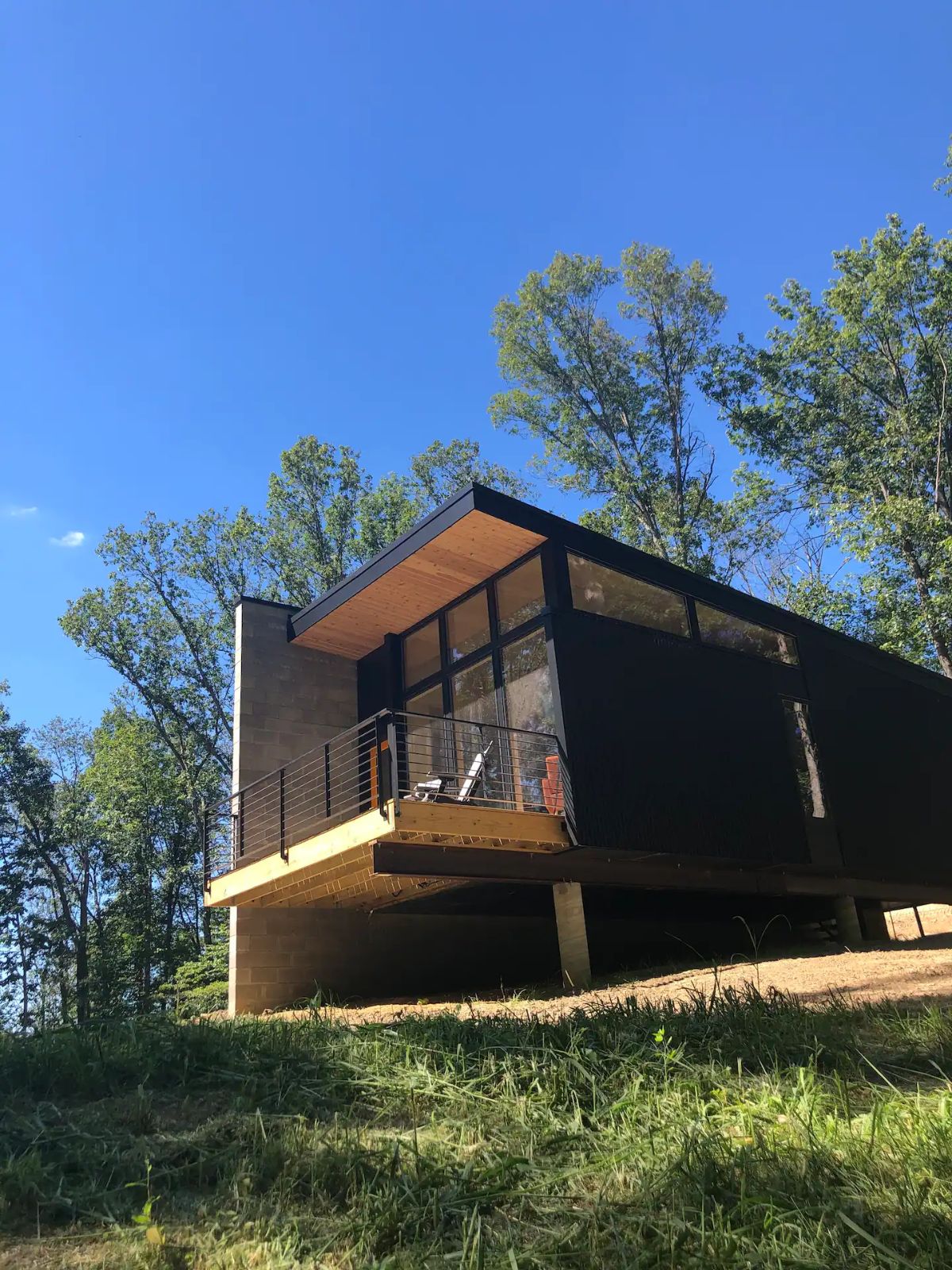 black tiny home with brown and concrete accents on balcony