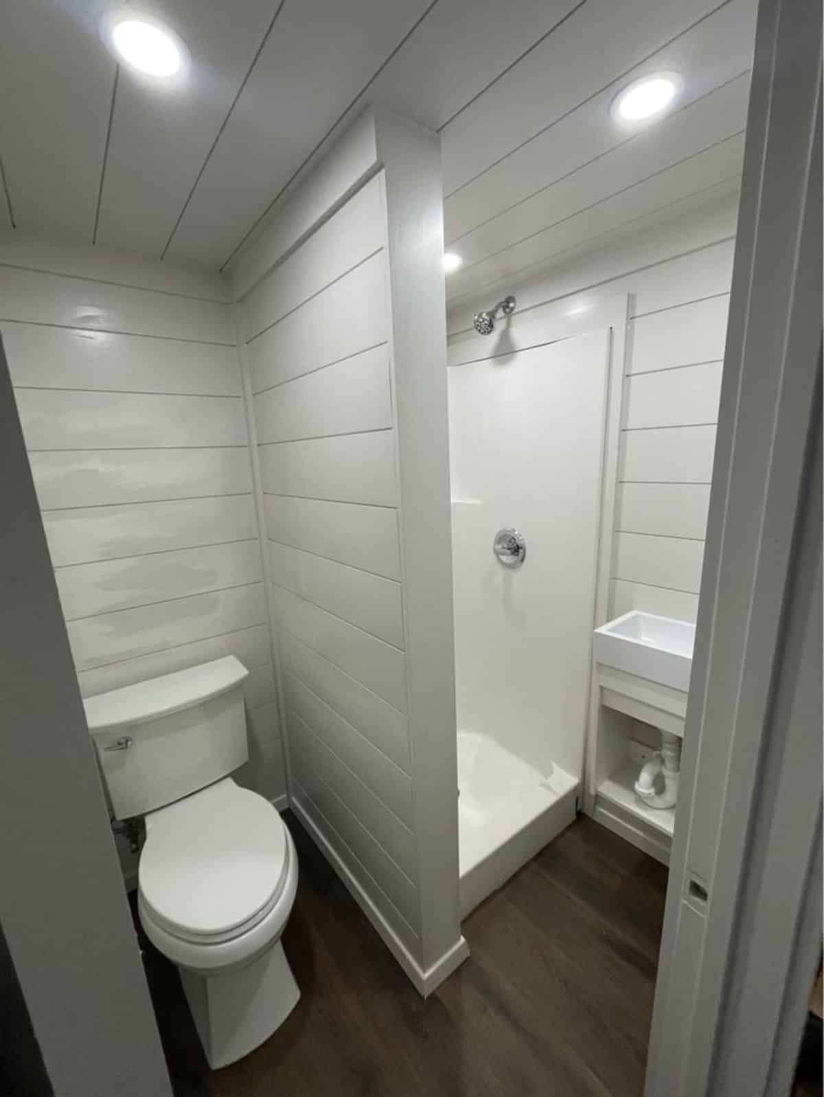 Bathroom of rustic 30’ tiny house has all the standard fittings with separate shower area