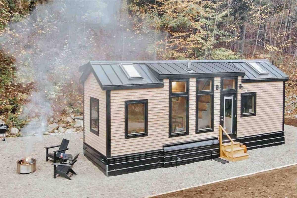 light wood tiny home with wall of windows on side and black trim and roof