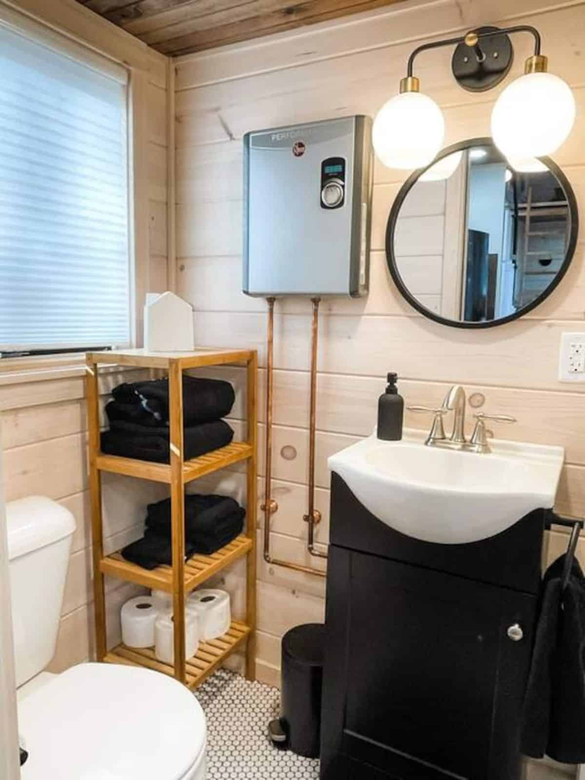 dark wood vanity cabinet below white sink with round mirror above in bathroom