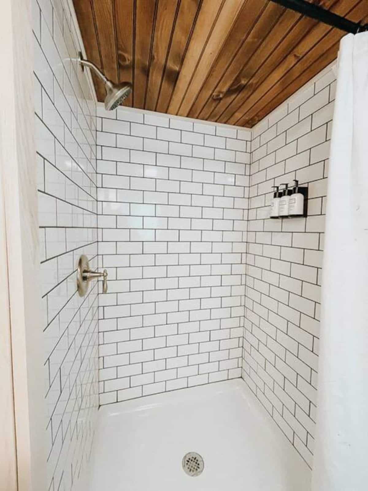 white subway tile shower stall with wood ceiling