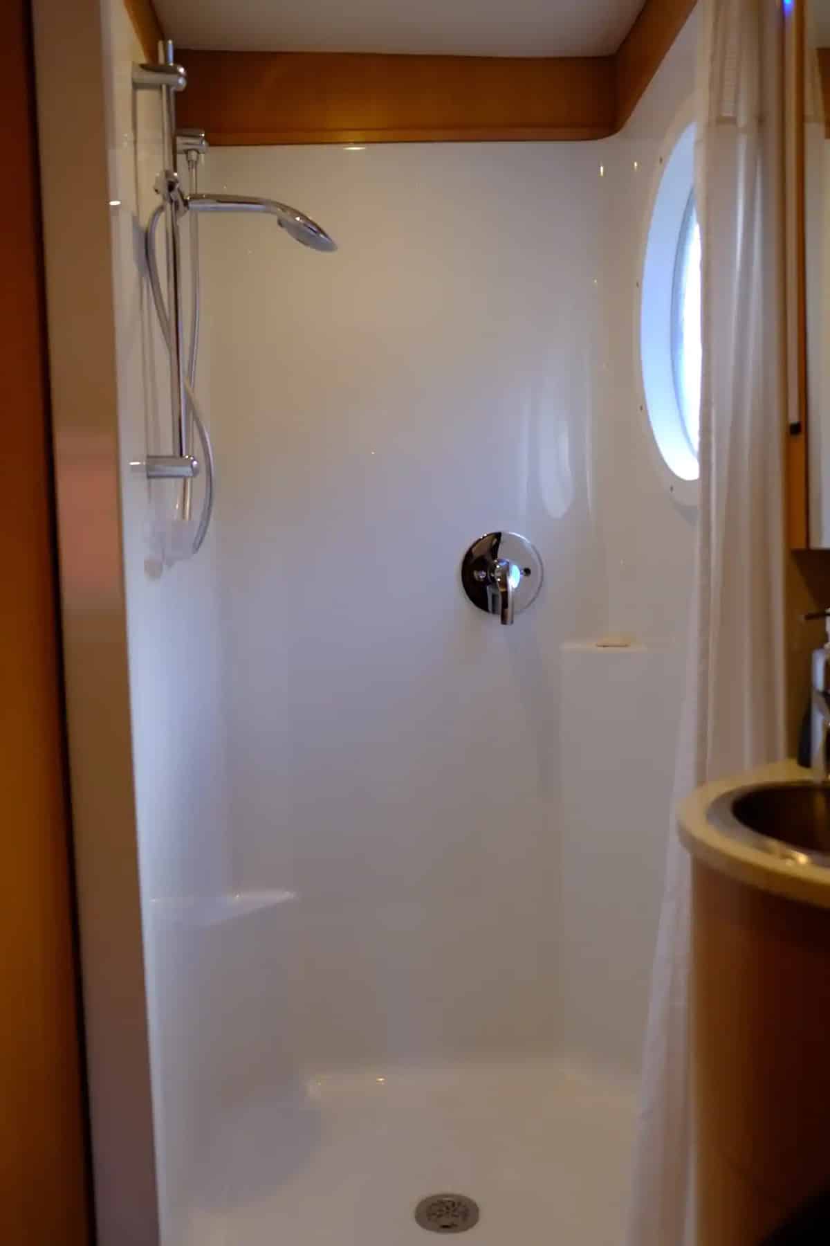 A large square shower stall with a large round "porthole" window ensures a comfortable shower experience while enjoying the serene surroundings.