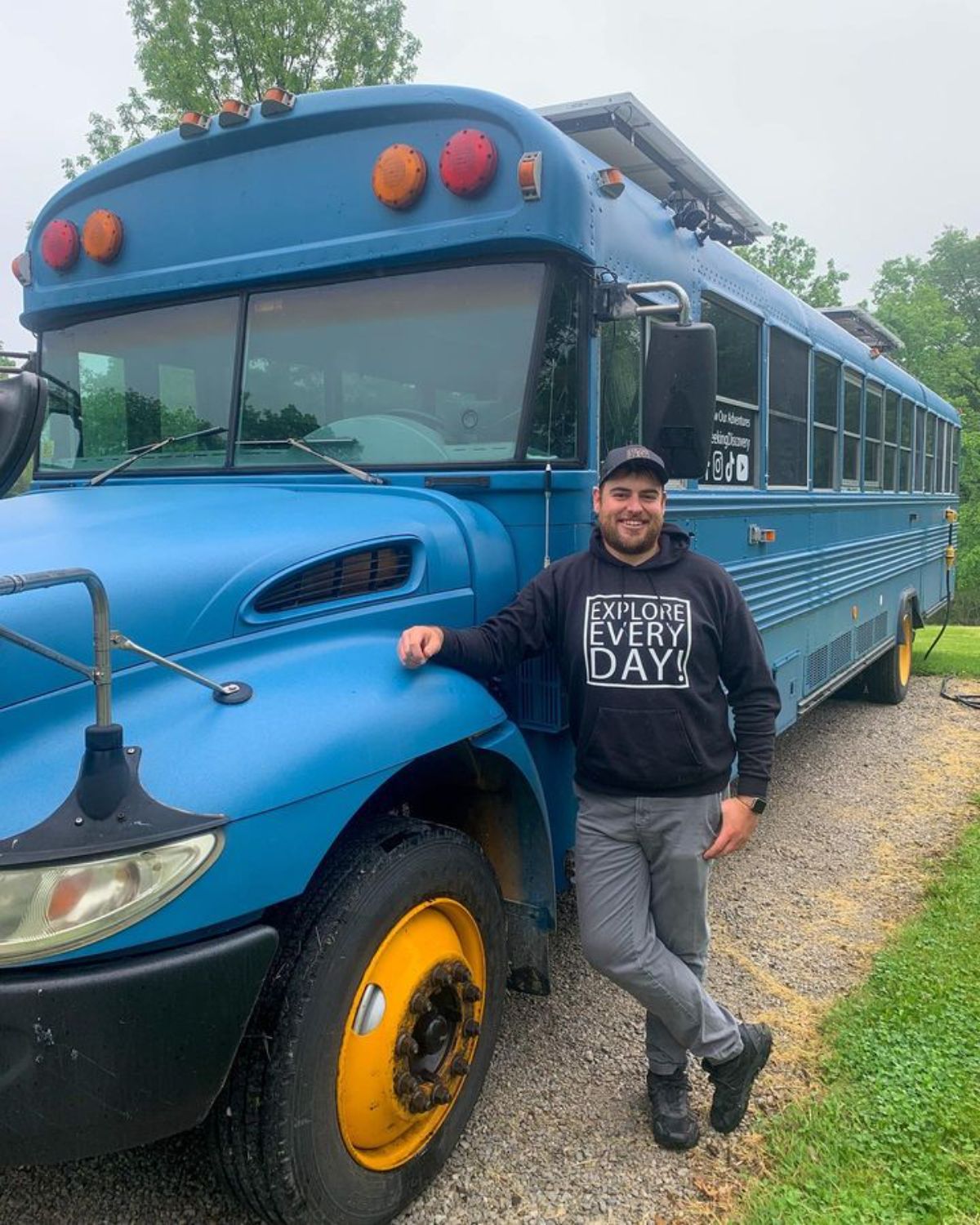man standing by front of blue bus tiny home