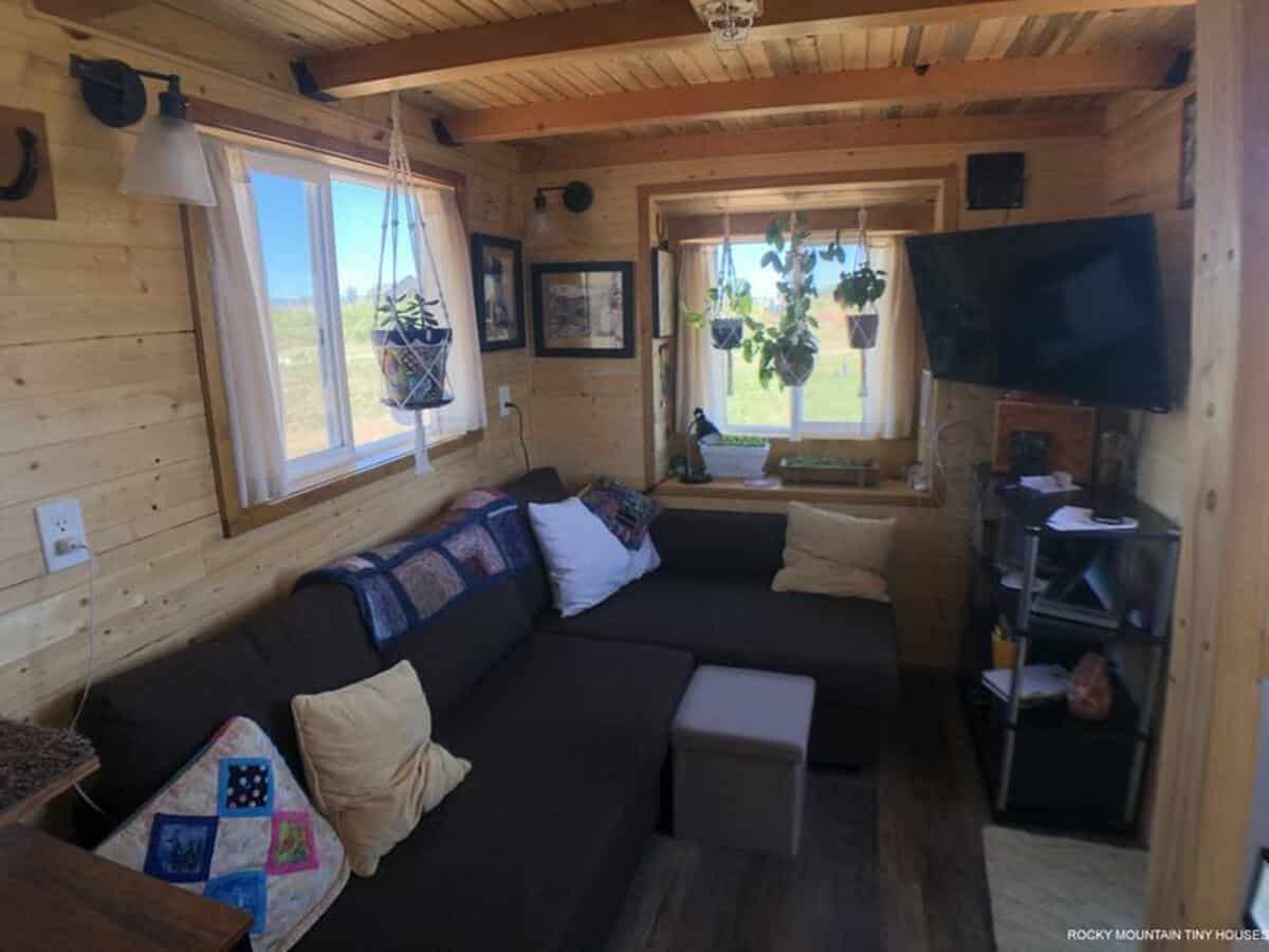 Living area of tiny house with ample space, knotted pine walls and ceiling, and natural 4x4 timbers supporting loft