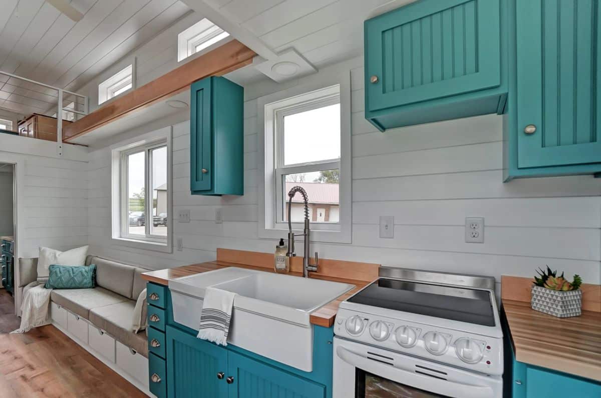 teal cabinets under white farmhouse sink by white stove