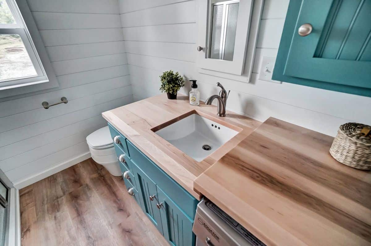 white sink inside wood countertop on teal counters