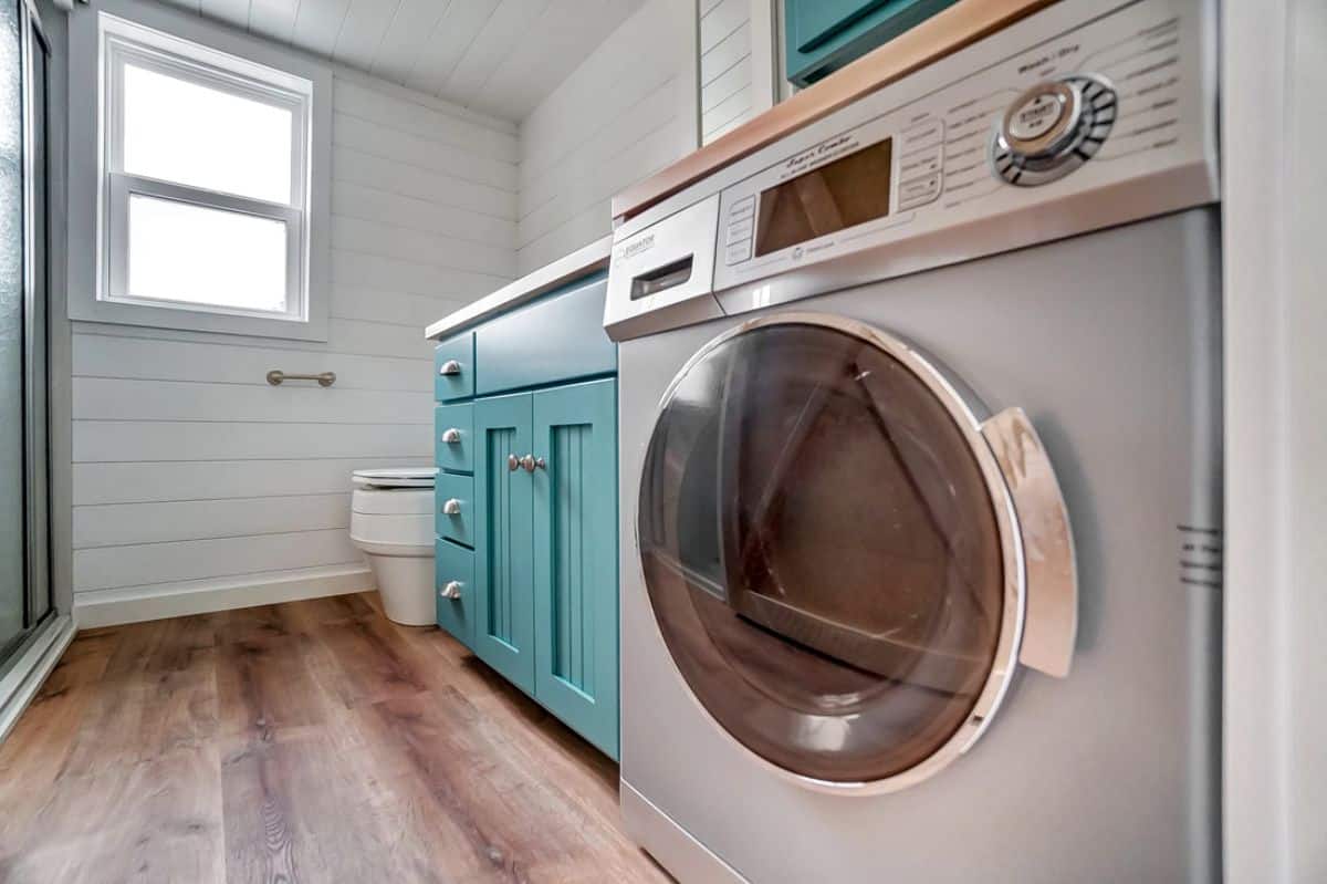 stainless steel combination washer and dryer next to teal cabinets