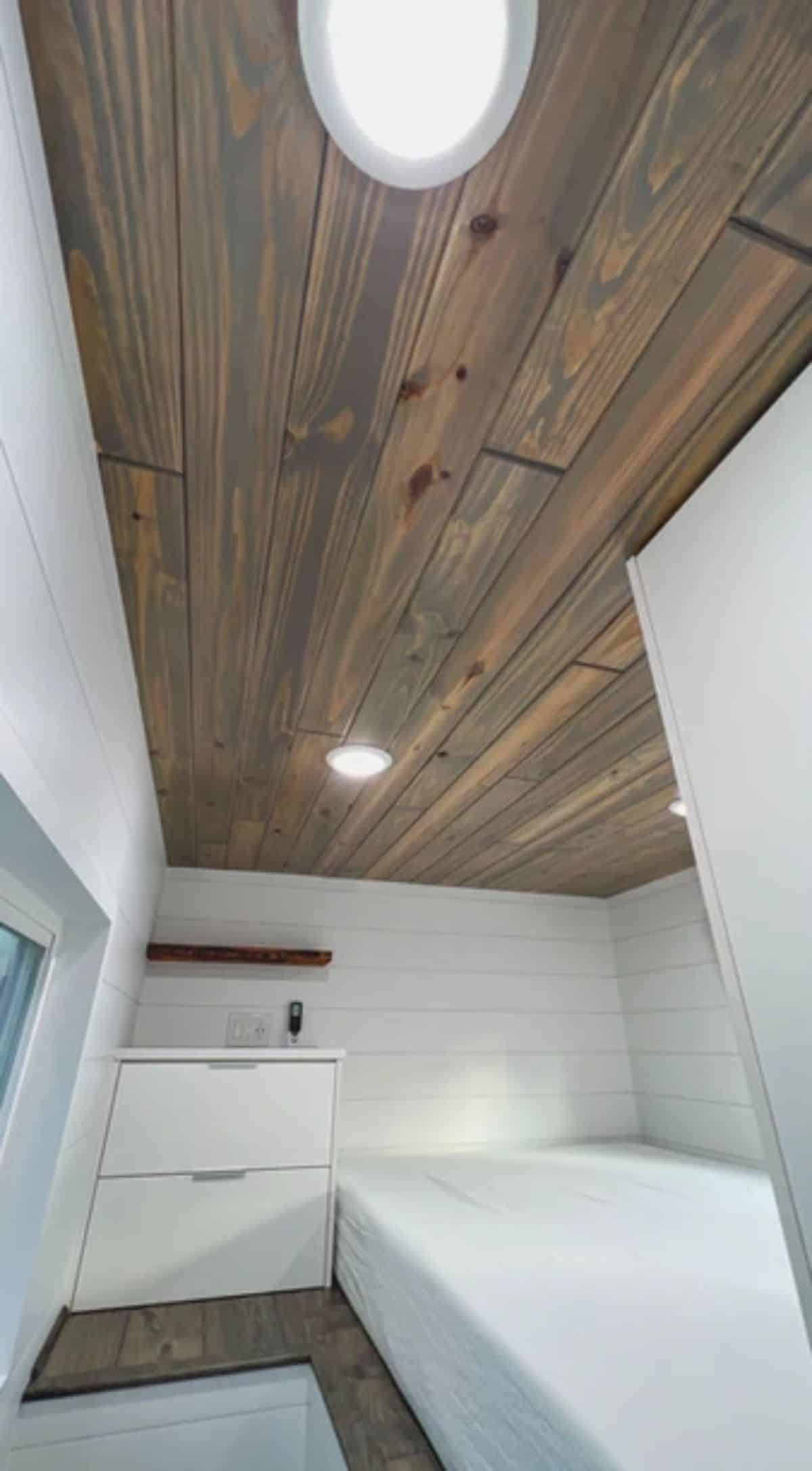 wood panel ceiling with white shiplap walls in standing loft sleeping area