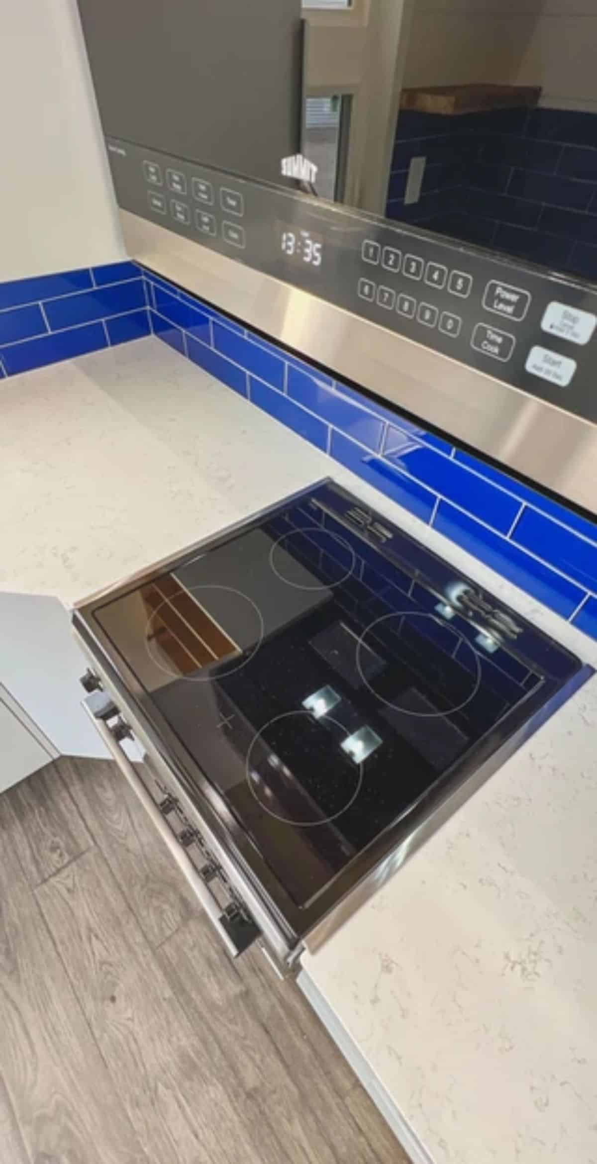flat top electric stove in kitchen with blue backsplash