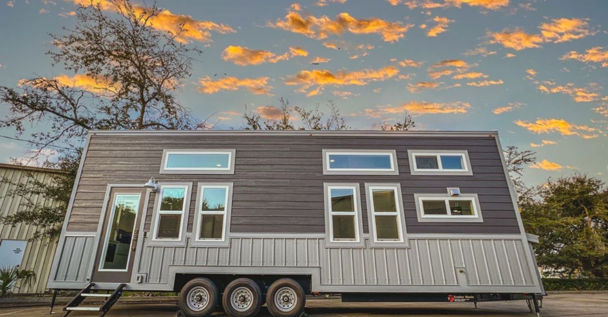 sunset clouds behind tiny home with gray and white siding