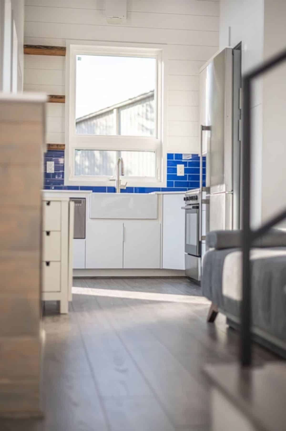 white cabinet sin l-shape kitchen with blue backsplash