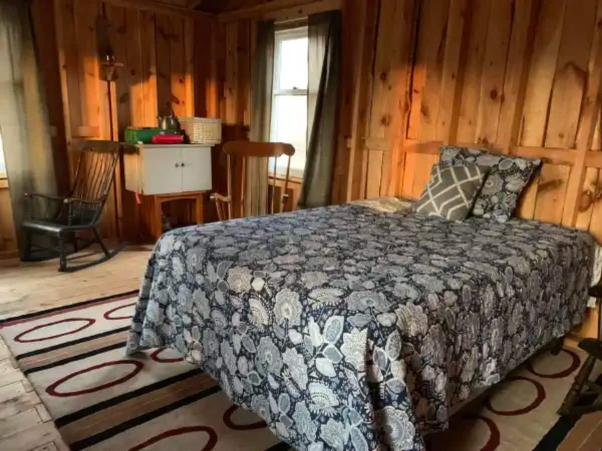 bed against wall with rug below inside cabin
