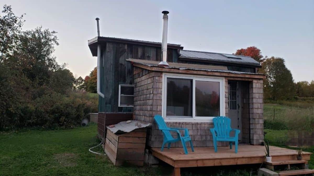 stunning off grid tiny home from outside with porch and chairs with steps