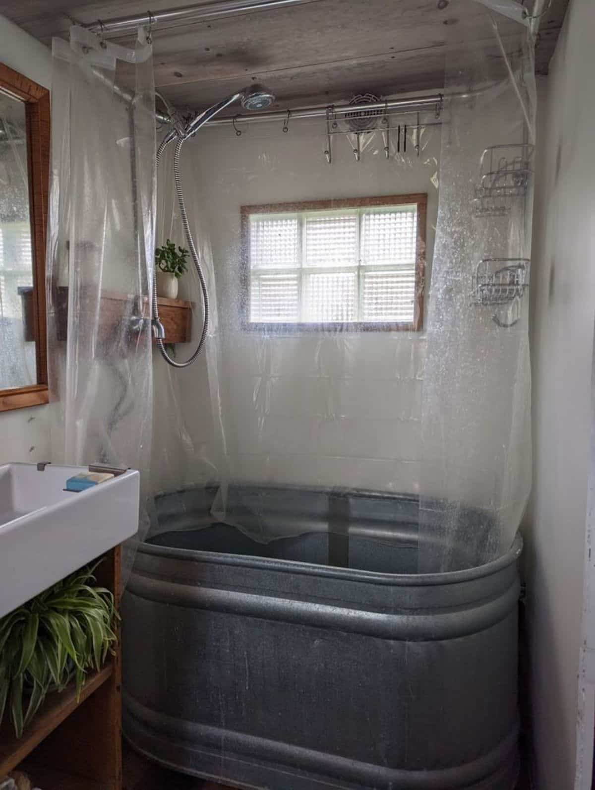 a steel bathtub with shower is installed in bathroom of off grid tiny home