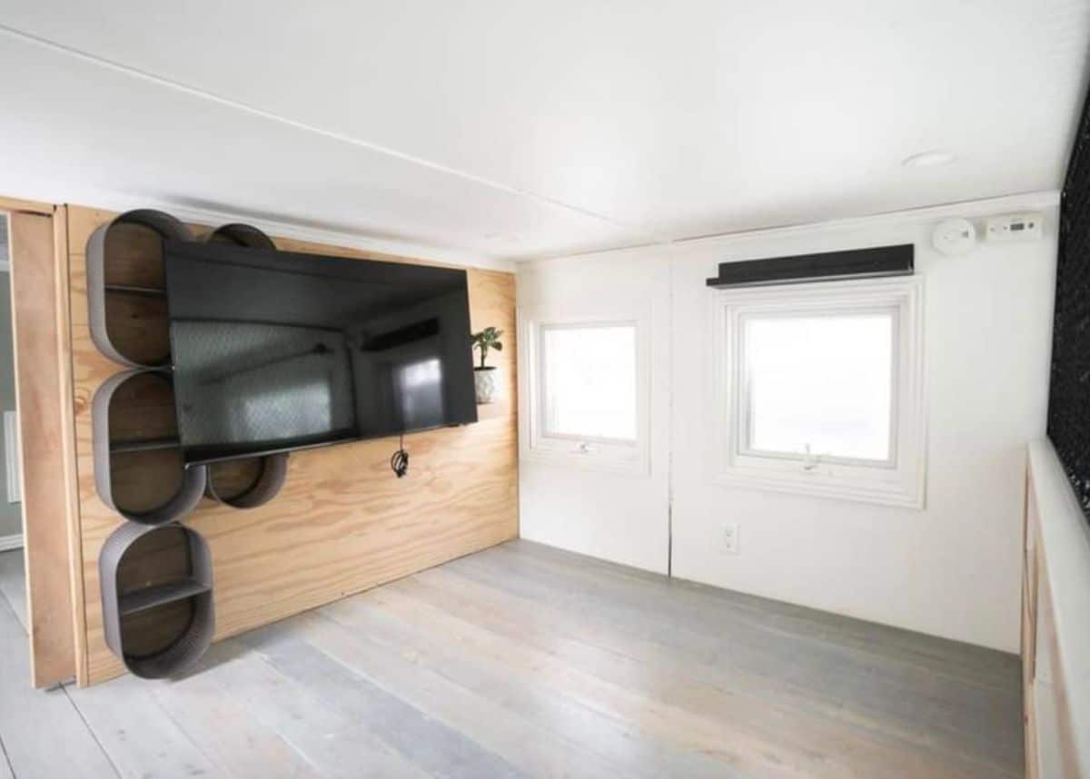 Wall mounted TV with storage racks with huge windows on loft bedroom