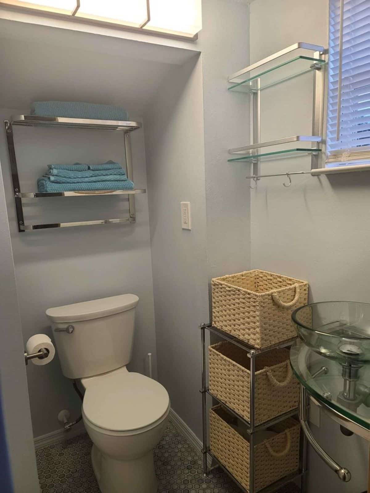 standard toilet and open shelves in bathroom of tiny house with deck