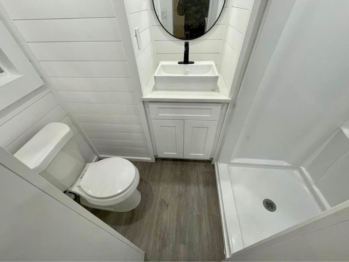 bathroom has standard toilet, sink with vanity & mirror and separate shower area