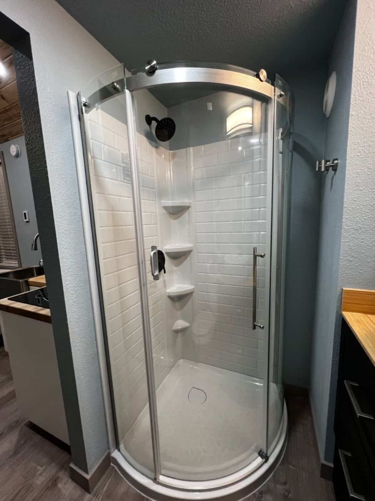 glass surround shower area of tiny home with downstairs bedroom