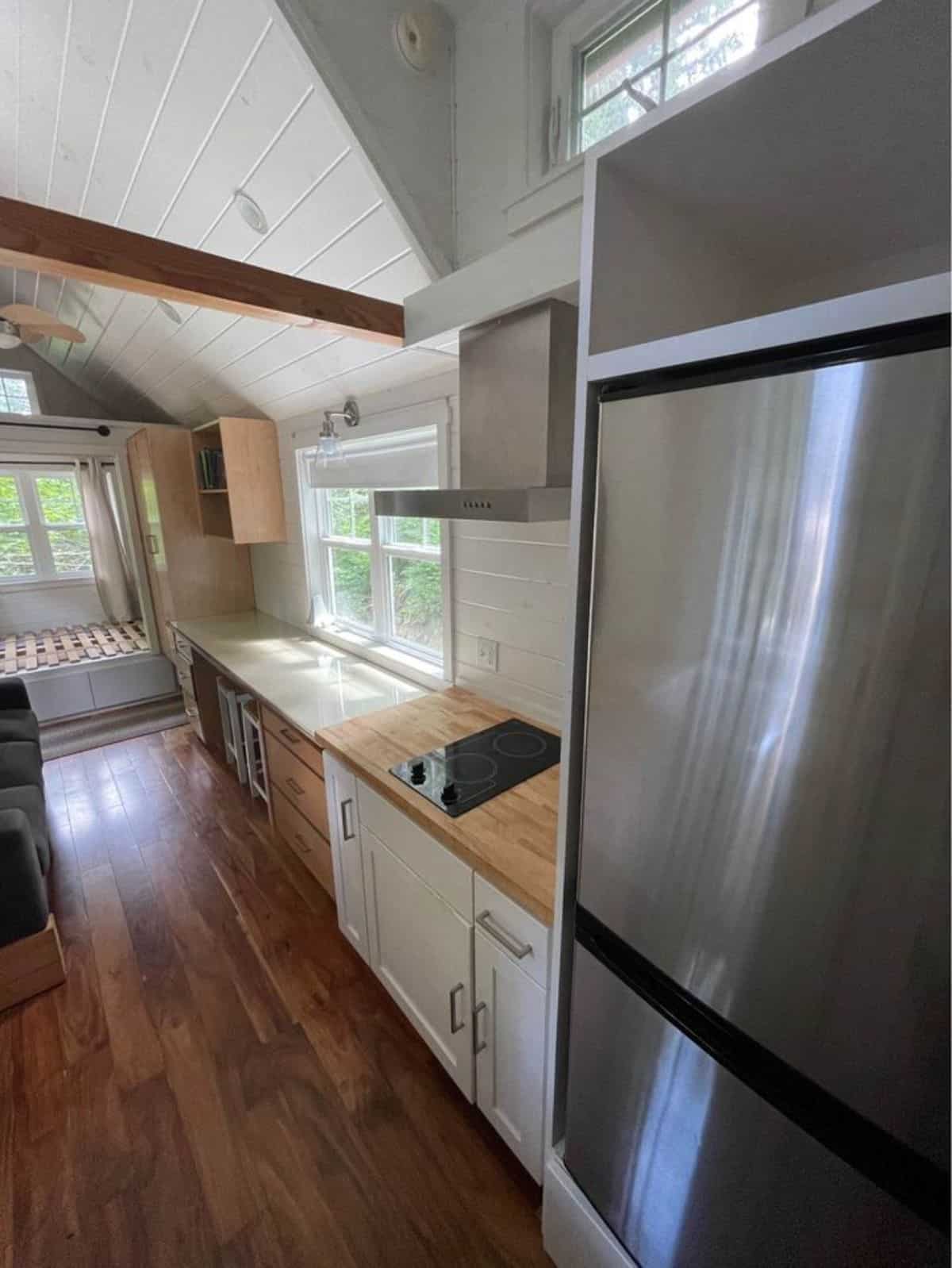 1 side of kitchen area has refrigerator, countertop and stove