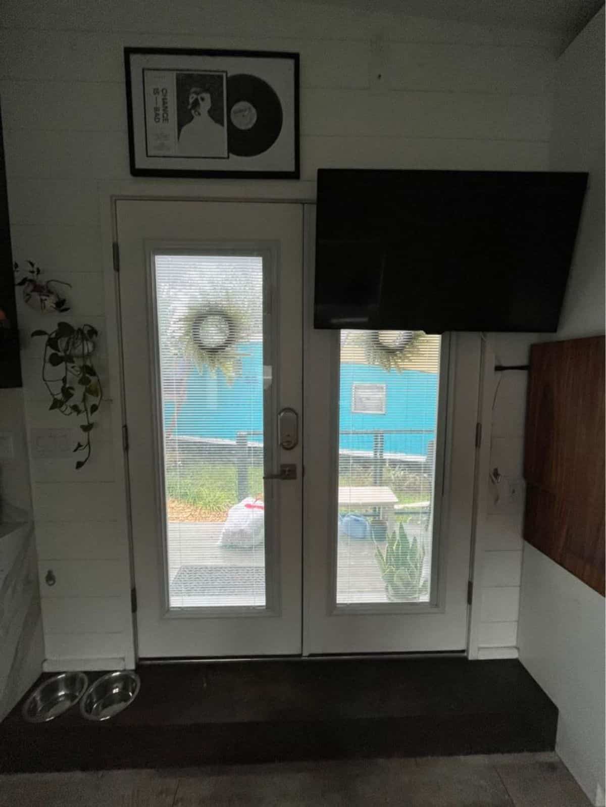 main glass door of tiny house in lakefront community has a wall mounted TV set
