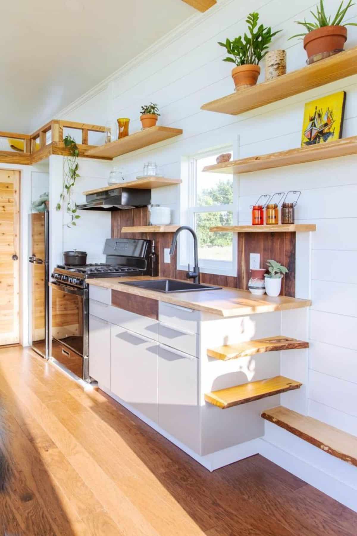 Well organized and furnished kitchen area of one bedroom tiny home with all the appliances and storage