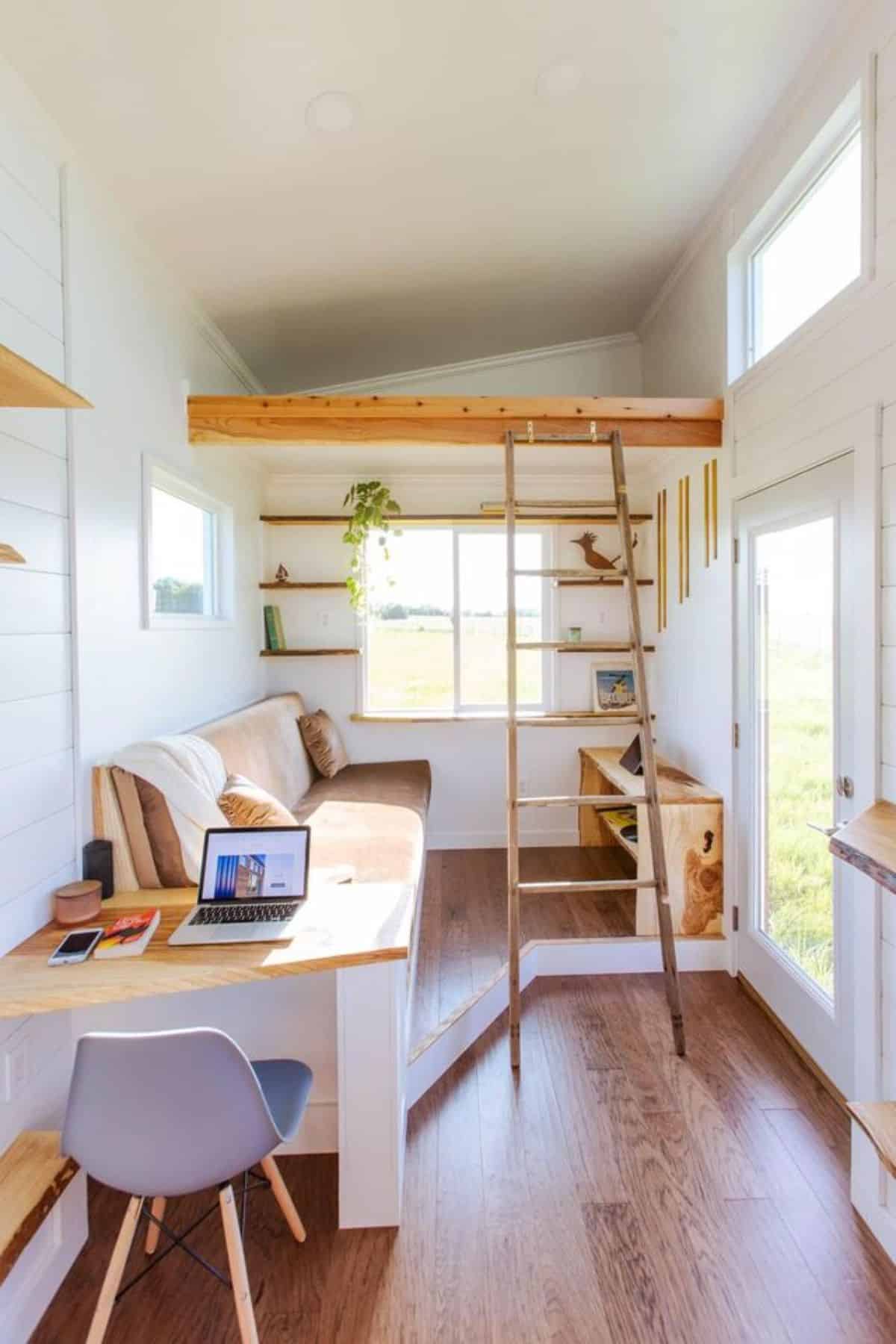 Work desk with chair and loft above the living area of one bedroom tiny home