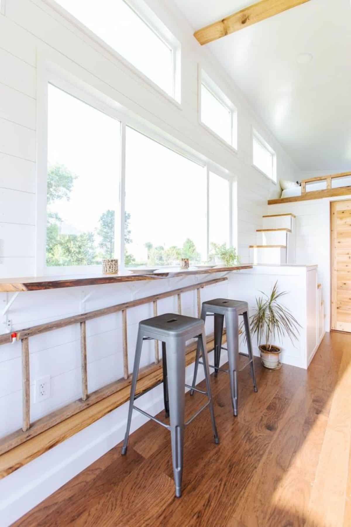 Dining area besides the huge window and stairs leading to the loft bedroom of one bedroom tiny home