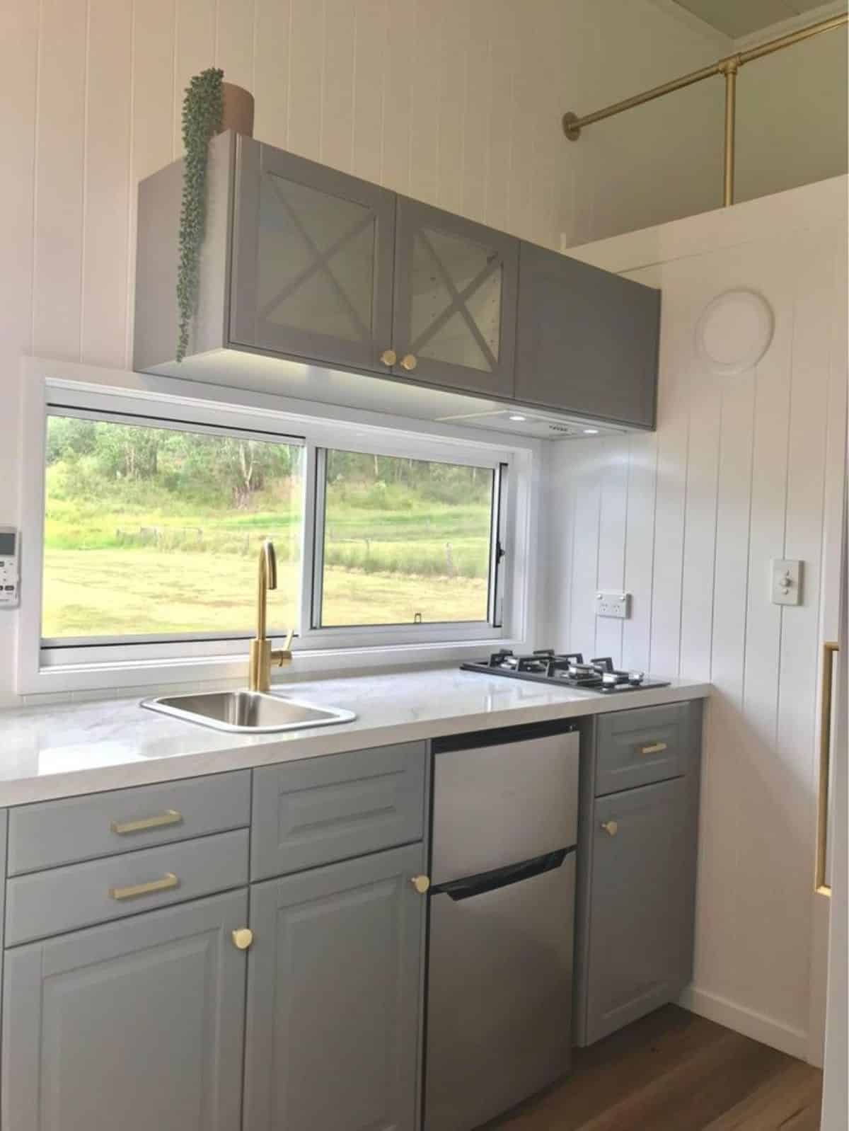 Stylish and well organized kitchen of furnished tiny house has all the necessary appliances and storage cabinets