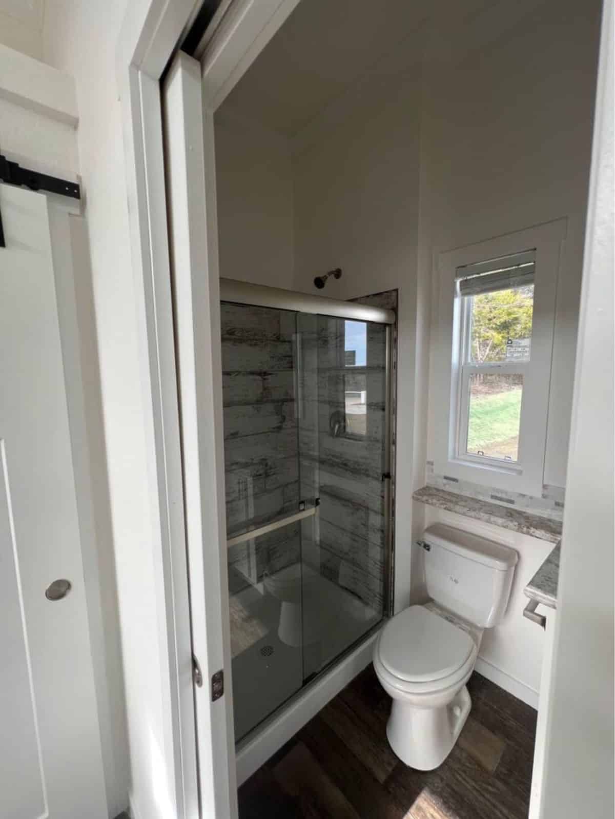 standard toilet and separate shower area in bathroom of tiny house with a porch