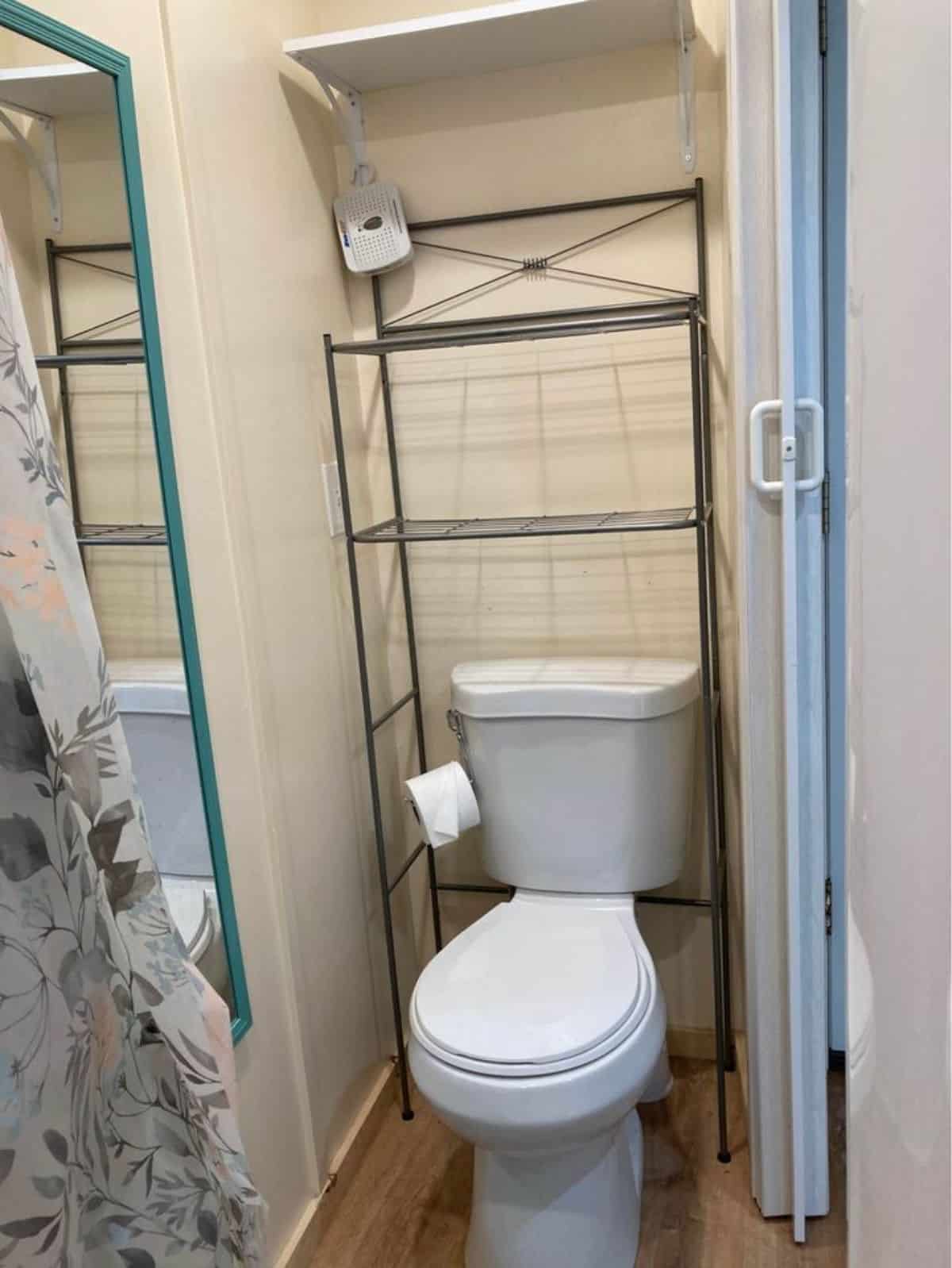standard toilet with storage racks behind the toilet in bathroom