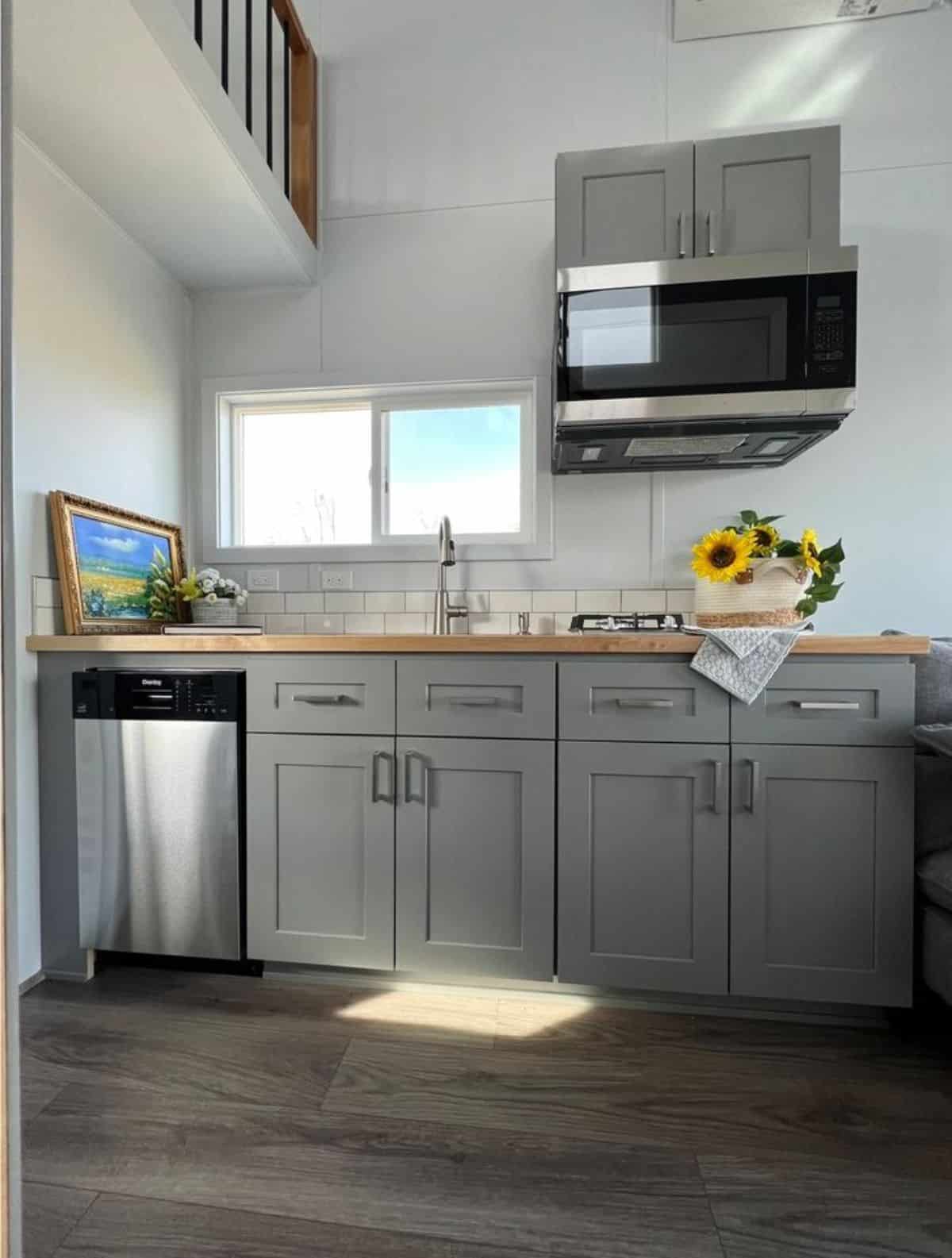 kitchen area of tiny house has all the essential appliances and storage cabinets
