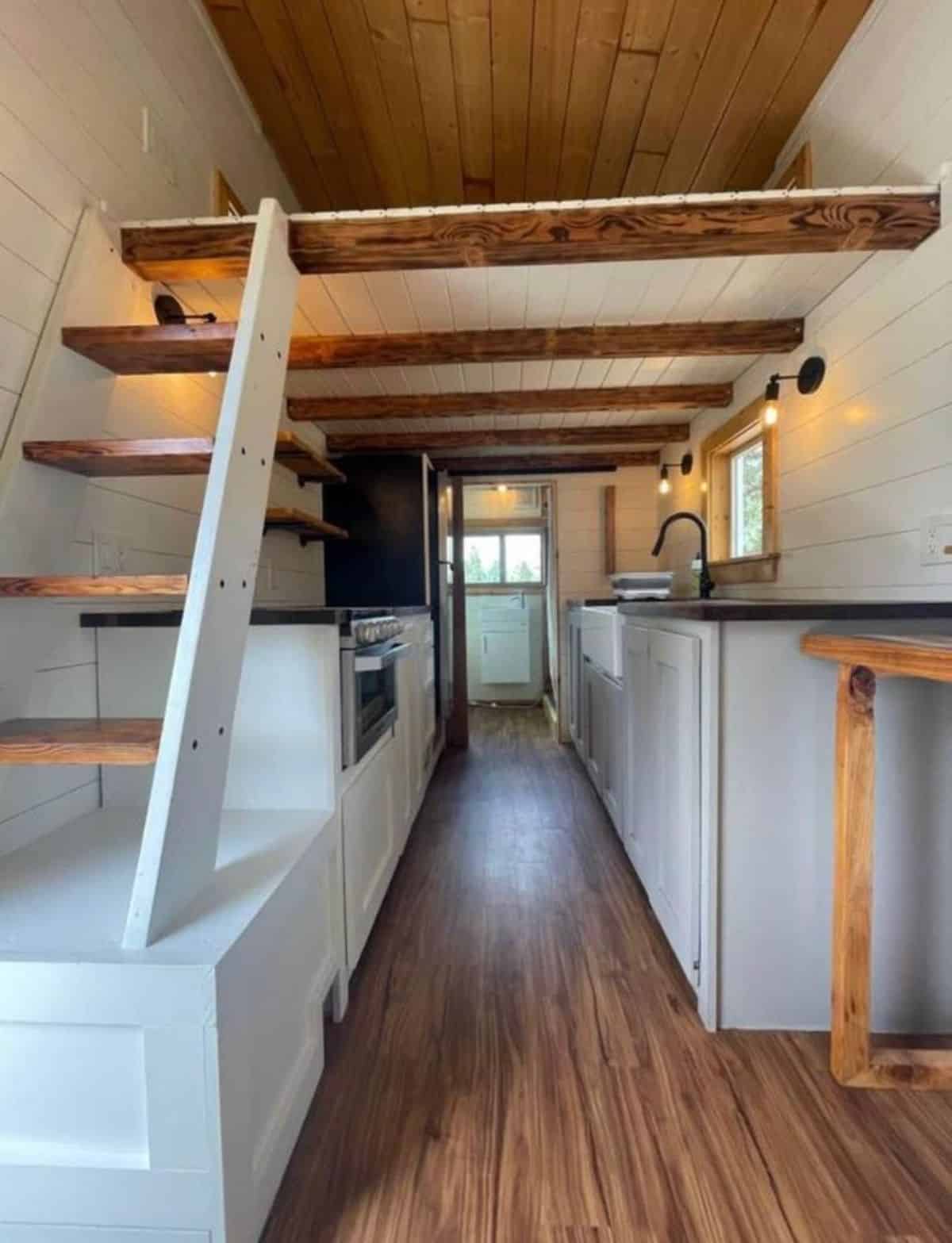 appliances and bar top table present in the kitchen area of 23’ tiny house