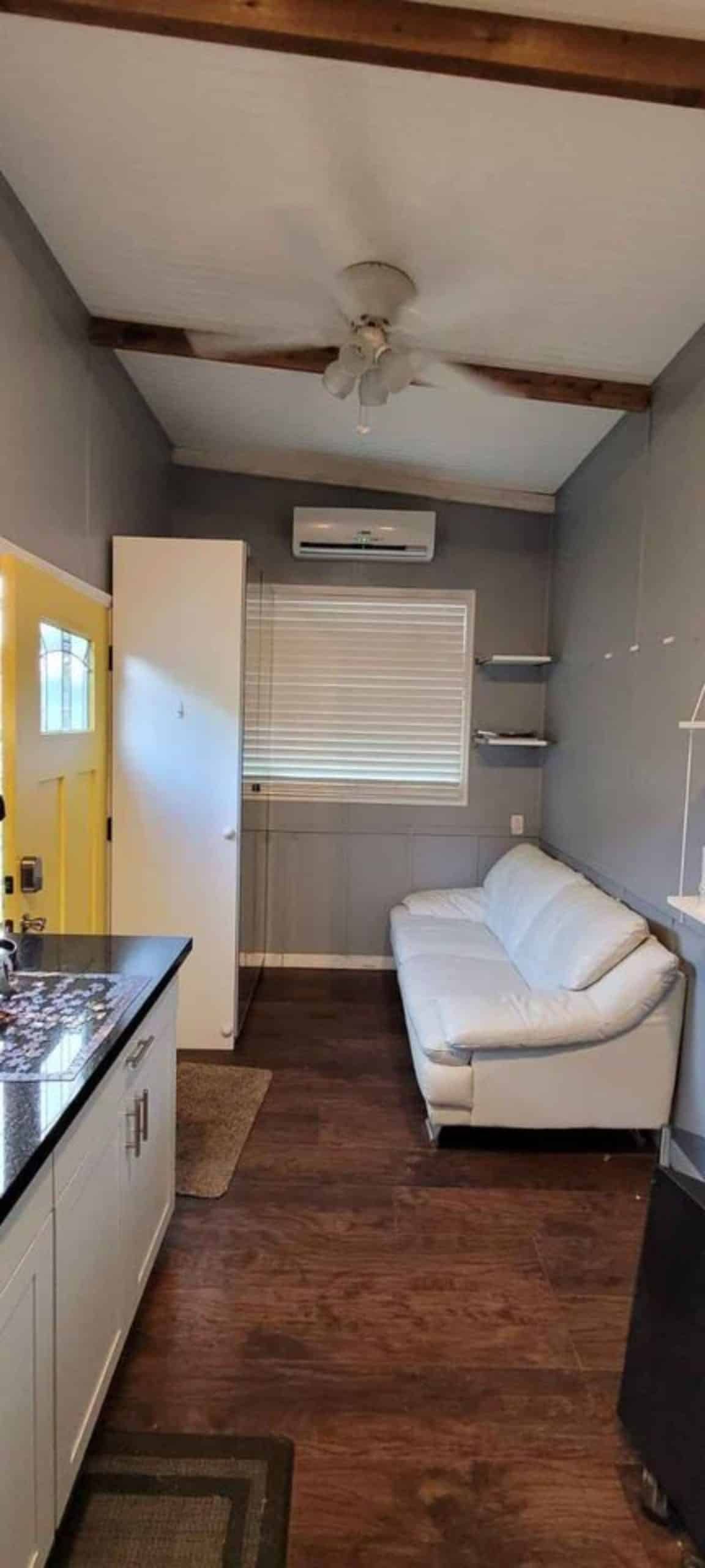 living room of 24' one bedroom tiny house has a very cozy and comfortable couch with air condition unit  
