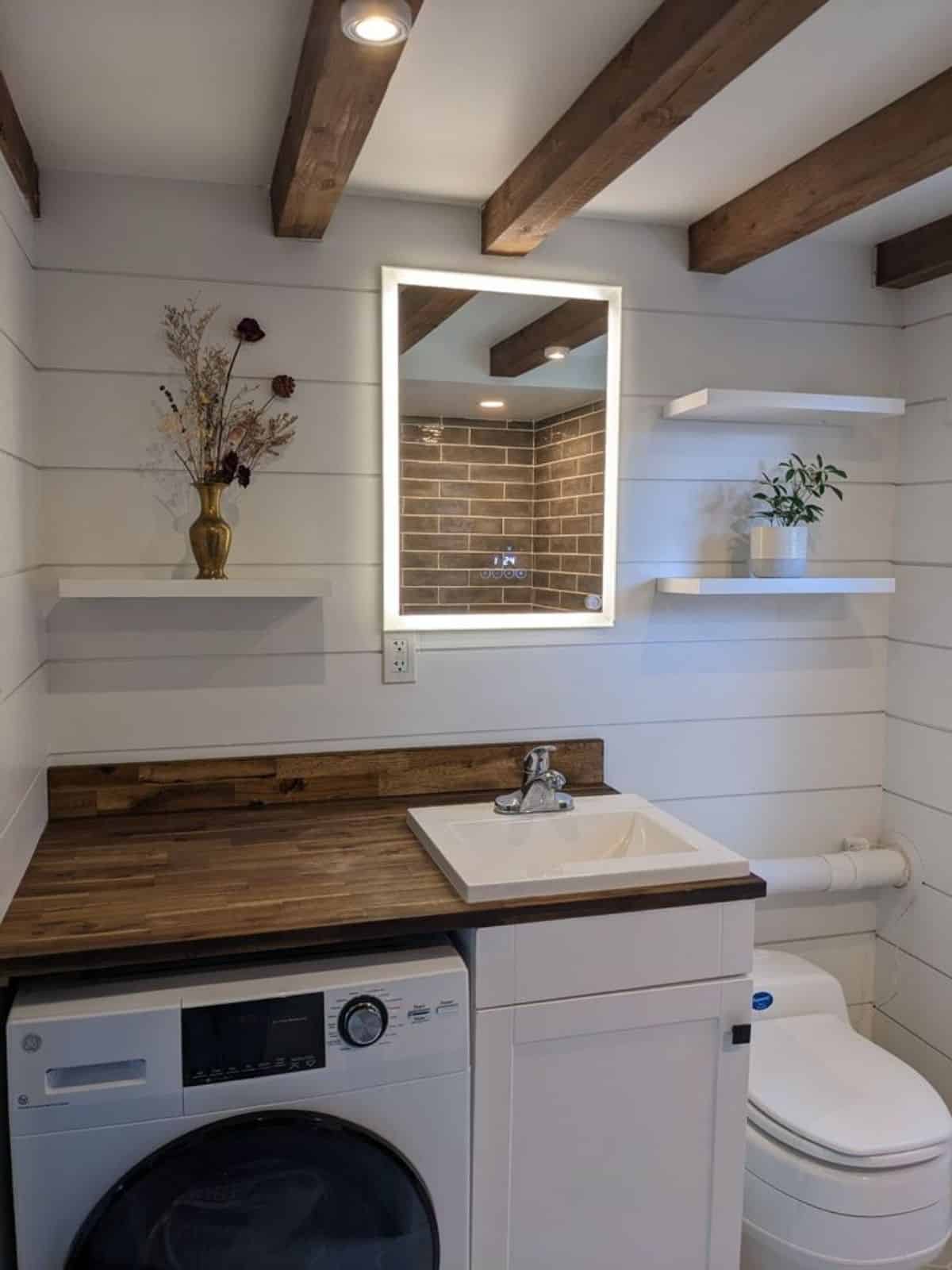 sink with vanity and washer dryer combo, plus LED and defog mirror in bathroom