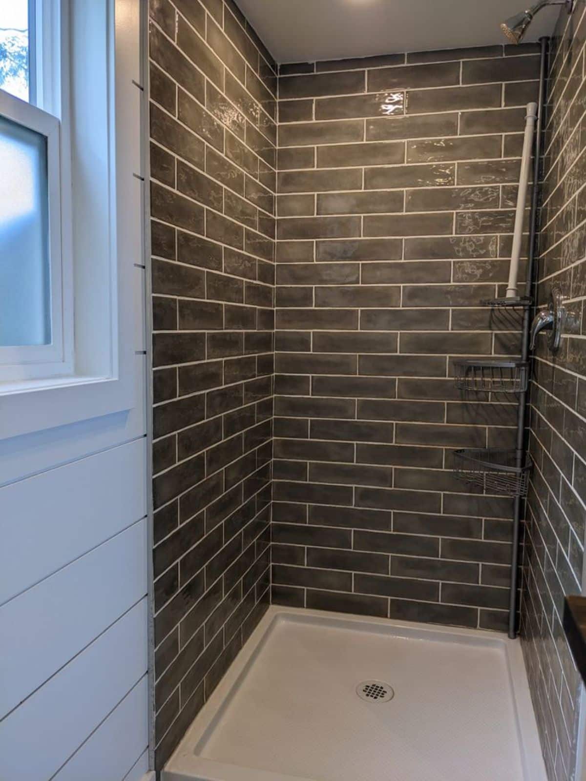 full length tiled shower area with head shower in bathroom