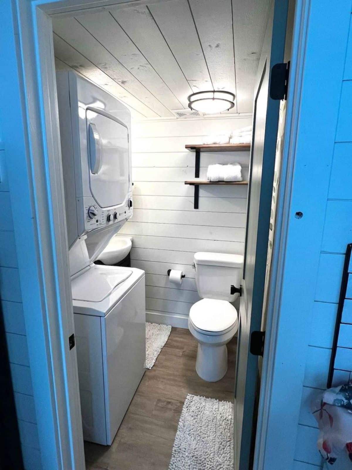 washer dryer combo and standard toilet with sink and vanity in bathroom of 28' luxury tiny home
