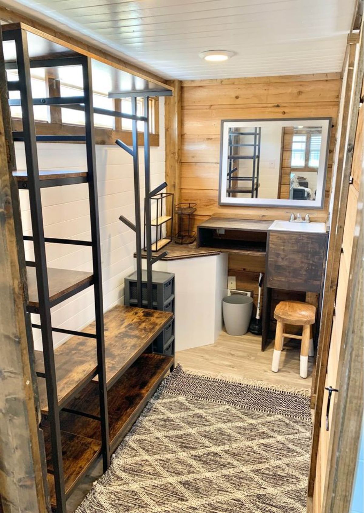 bathroom of 28’ NOAH certified tiny home has sink with vanity and all styled wooden racks