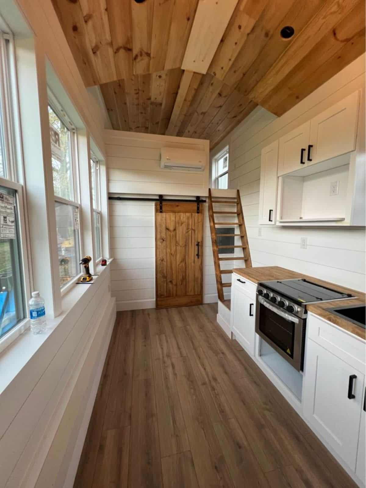 white walls, vinyl flooring and huge ceiling of 28’ tiny farmhouse