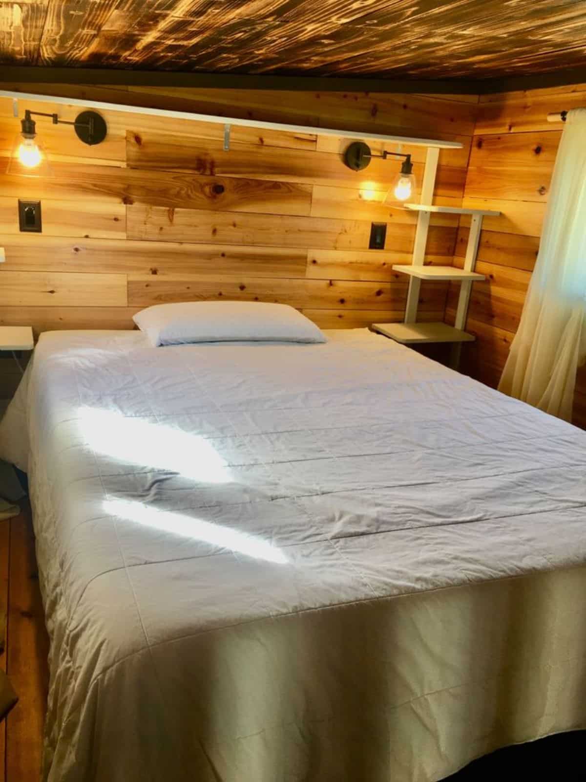 main floor bedroom of tiny home with two bedrooms has a very comfortable bed with ample space left for other items