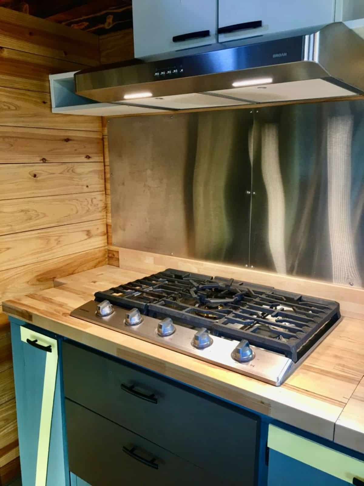 stainless steel range hood burner with led lights in installed in kitchen area of tiny home with two bedrooms