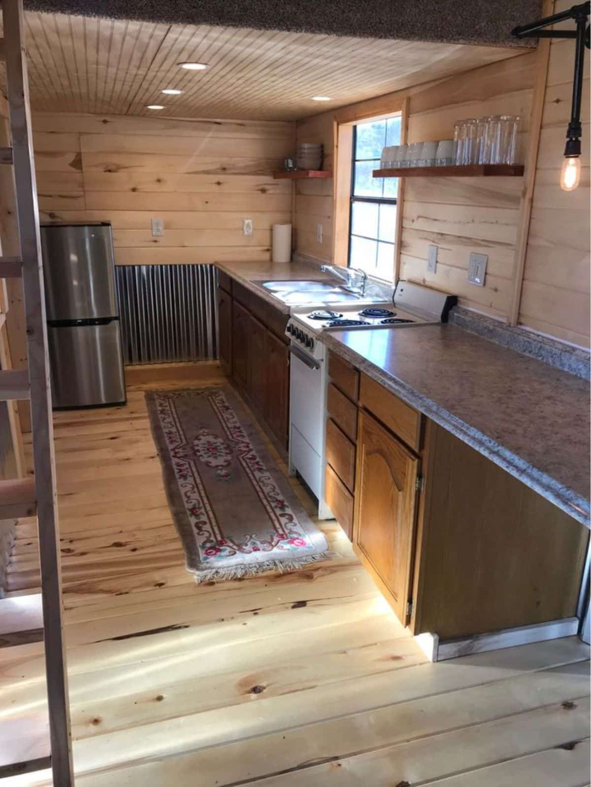 kitchen area of $55k double lofted tiny home is long with all the necessary appliances