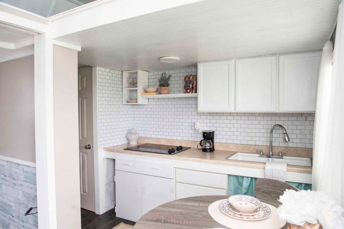 kitchen area is right besides the bathroom of adorable tiny home