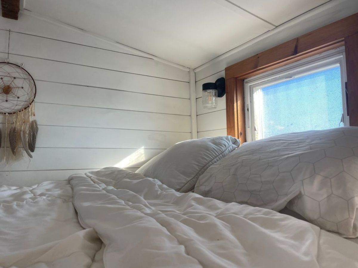 loft area of custom tiny home has a comfortable bed