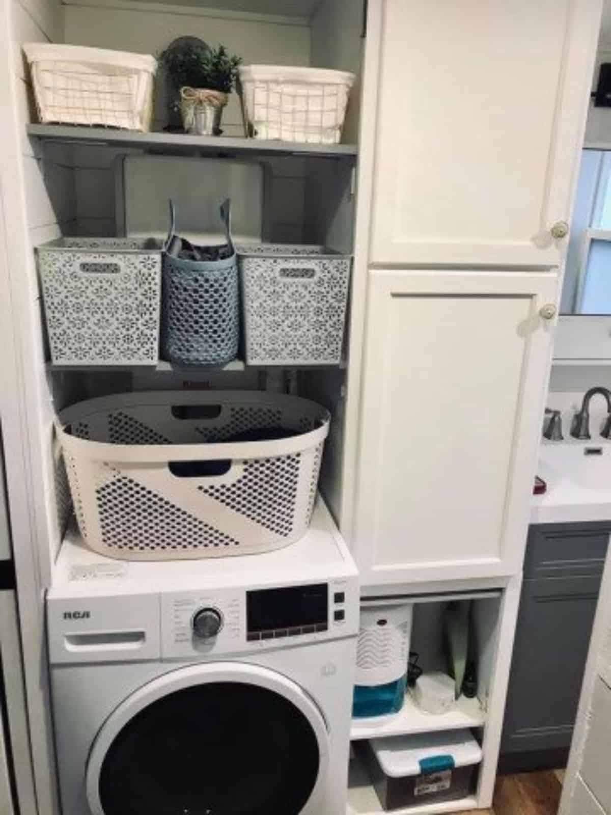 separate area for laundry and washer dryer combo with storage shelves in bathroom of fully furnished tiny home