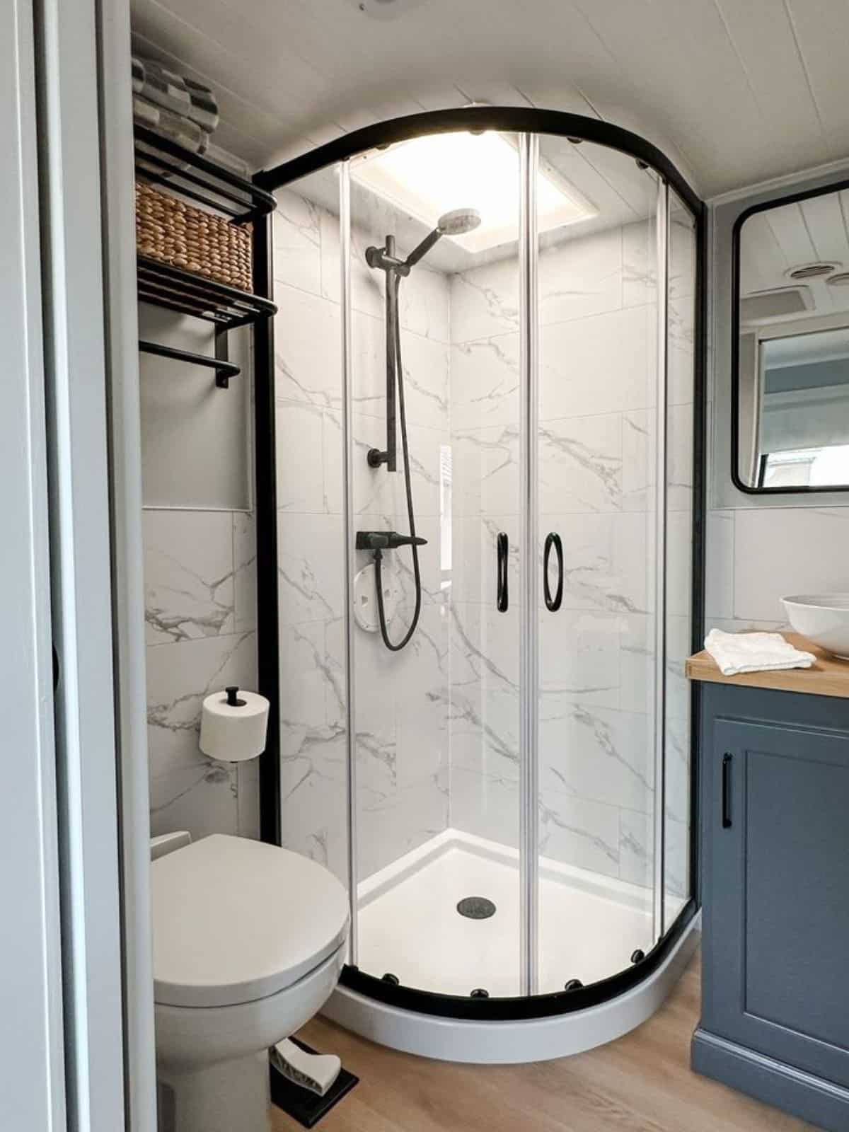 glass enclosure shower area and standard toilet in bathroom of remodeled RV
