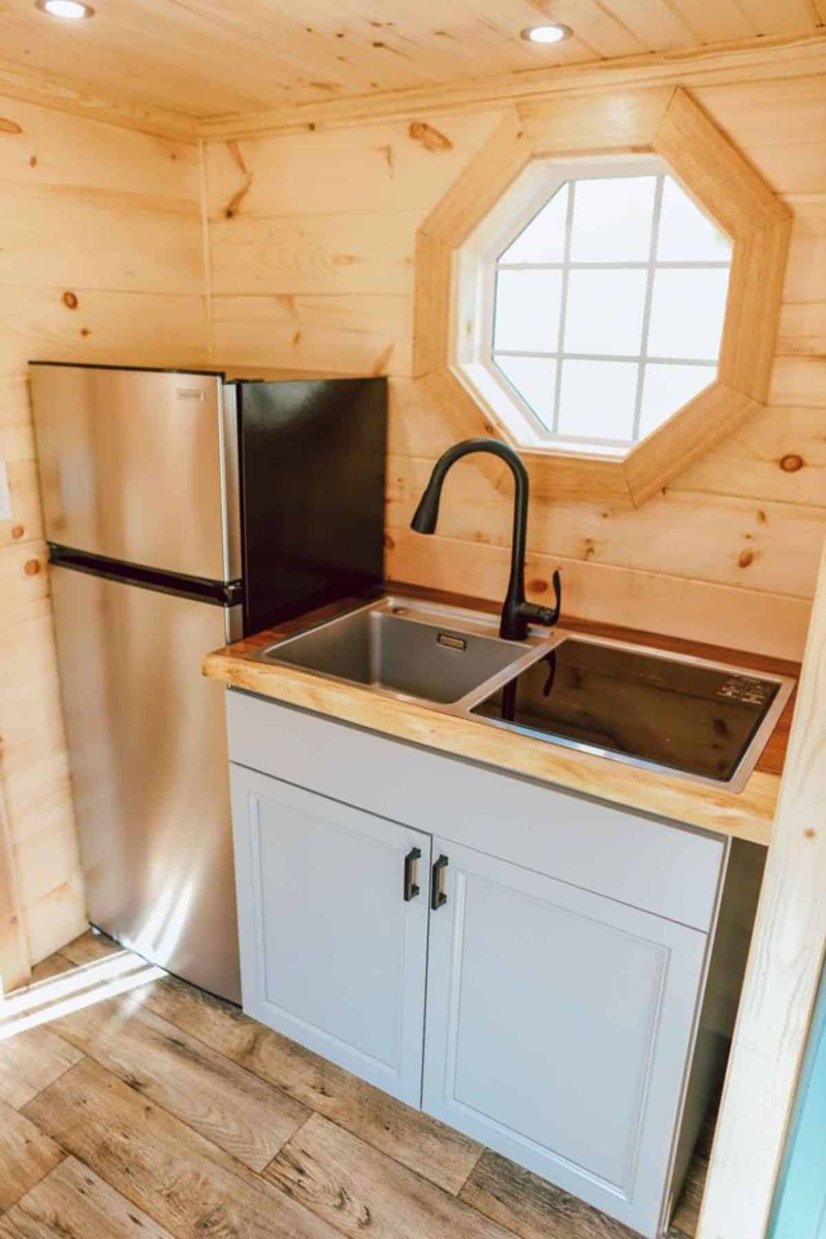 double door refrigerator and stainless steel sink is installed in the kitchen area of spacious tiny house on wheels